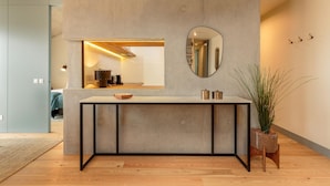 A modern kitchen with a concrete island, a large mirror, and a potted plant. - Feel Corporate Housing Campanh 05 (Porto)