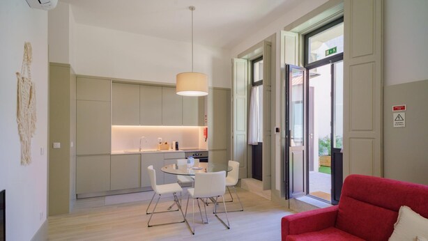 A modern interior with a dining area, kitchen, and a red sofa. - Feel Porto Matosinhos Ocean Flat V (Matosinhos)
