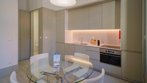 Una cocina moderna con una mesa de comedor de vidrio, electrodomésticos de acero inoxidable y un diseño minimalista.