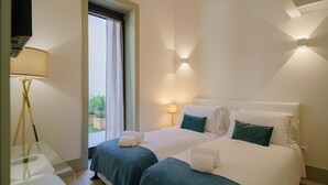 A hotel room with two beds, a bedside table, a lamp, and a view of the outdoors. - Feel Porto Matosinhos Ocean Flat V (Matosinhos)