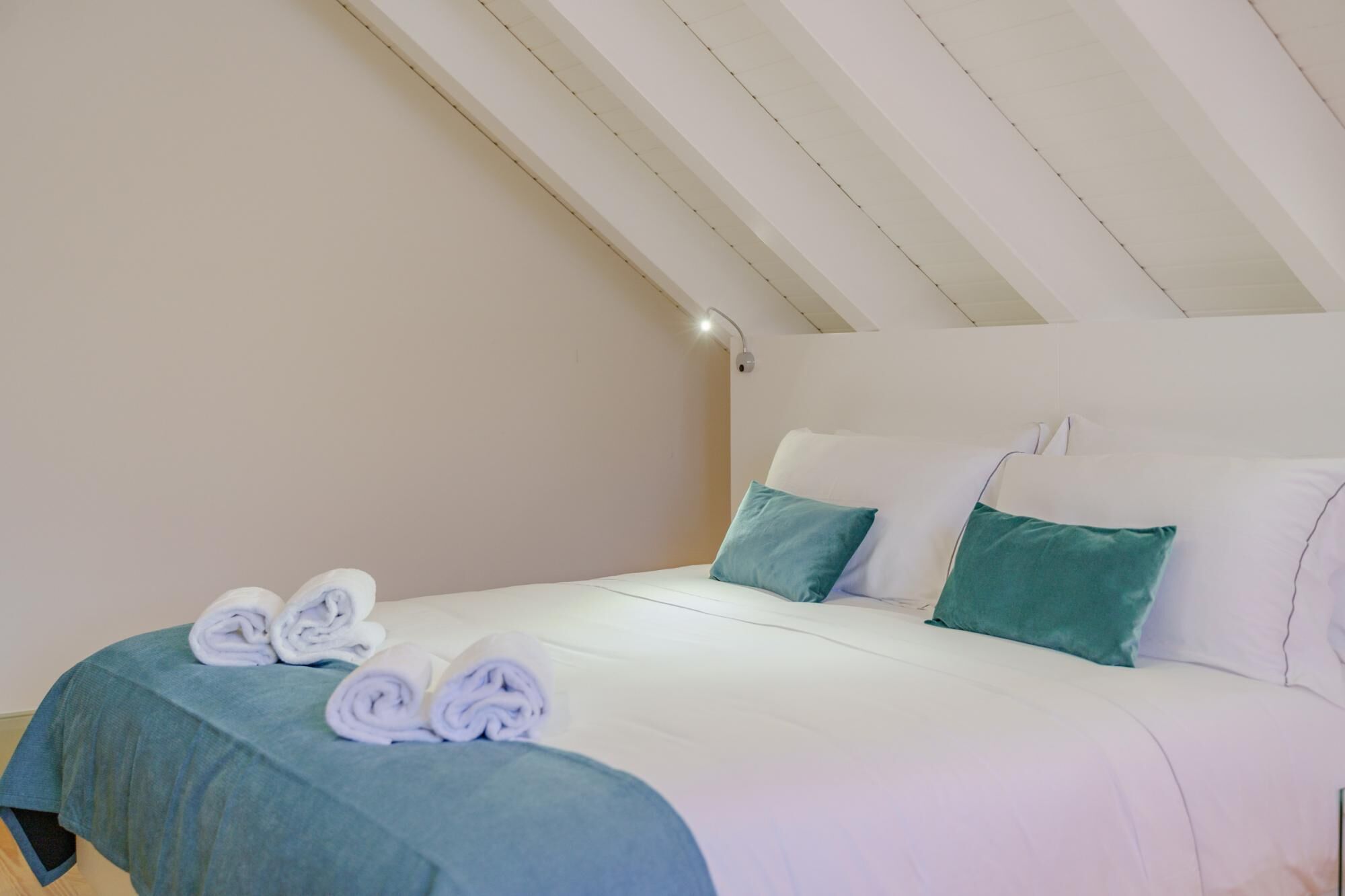 Quarto com cama, travesseiros e toalhas dobradas.
