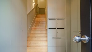 Una escalera de madera conduce a un rellano con una puerta de color claro y un picaporte de metal.