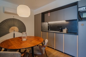 A modern kitchen with a built-in stove, a round wooden dining table, and a large fan.
