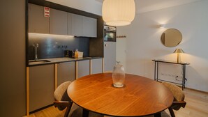 Una cocina moderna con electrodomésticos de acero inoxidable, una mesa redonda de madera y una lámpara colgante.