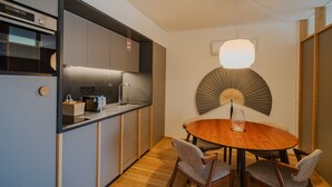 Una cocina moderna con horno empotrado, un comedor con mesa y sillas de madera redondas, y una lámpara de techo con ventilador original.