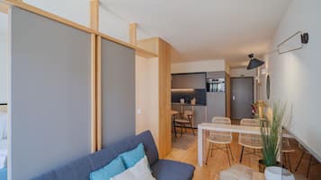 Uma sala de estar moderna com sofá, mesa de jantar e cadeiras, cozinha e escada.