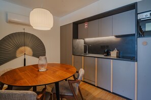 Una cocina moderna con horno empotrado, lavamanos y comedor con mesa redonda y sillas.