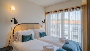 A hotel room with two beds, a large window with curtains, and a wall-mounted lamp. - Feel Corporate Housing Campanh 08 (Porto)