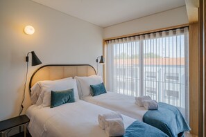 A hotel room with two beds, a large window with curtains, and a wall-mounted lamp. - Feel Corporate Housing Campanh 08 (Porto)