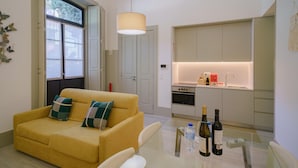Una sala de estar moderna con sofá, una mesa de comedor y una cocina con horno y lavaplatos integrados.