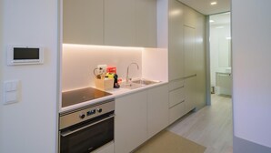 Una cocina moderna con horno empotrado, un lavamanos y un refrigerador compacto.