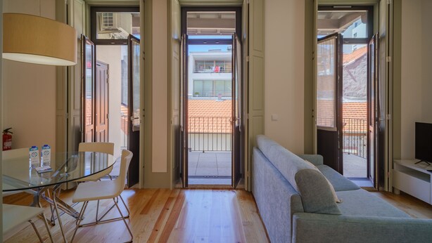 A modern living room with a glass table, a sofa, and a television. - Feel Porto Matosinhos Ocean Flat III (Matosinhos)