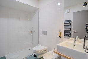 Une salle de bain moderne avec une douche à parois de verre, des toilettes, un bidet et un lavabo avec un miroir.