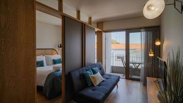 Un dormitorio moderno con cama, sofá oscuro y balcón con vistas.