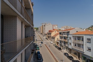 A multi-story building with balconies, a street with parked cars, and other buildings in the background. - Feel Corporate Housing Campanh 07 (Porto)