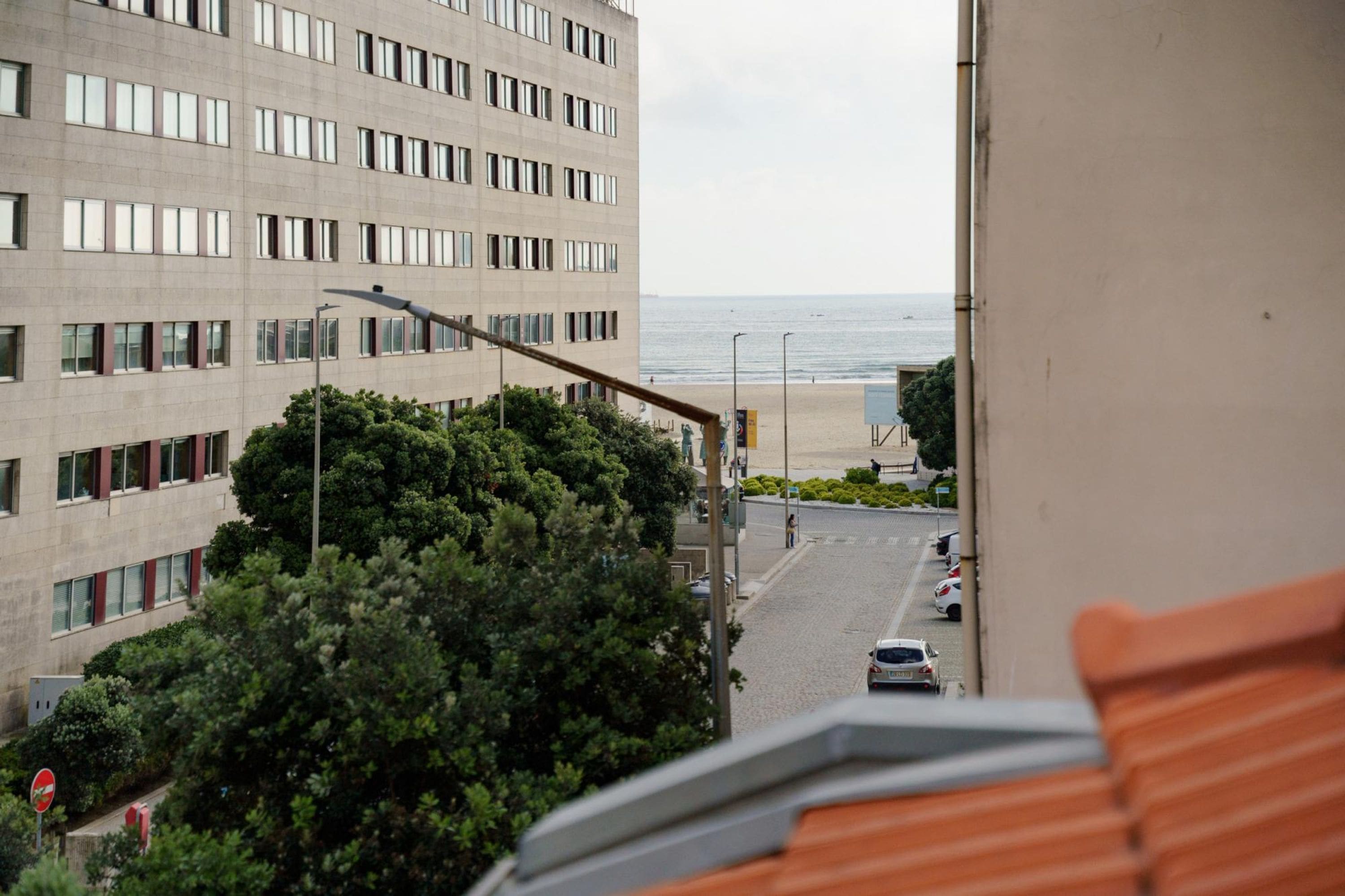 Vista de una calle que lleva a una playa, con un edificio en primer plano.