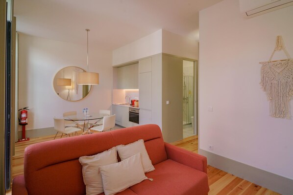 Una sala de estar moderna con un sofá rojo, un espejo redondo y un tapiz de macramé en la pared.