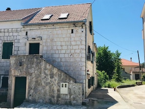 Un edificio de piedra con techo de tejas, una pequeña escalera y un estrecho sendero que conduce a otro edificio.