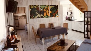 Una cucina moderna con mobili bianchi, un'area pranzo con tavolo e sedie, e una scala che conduce a un piano superiore.