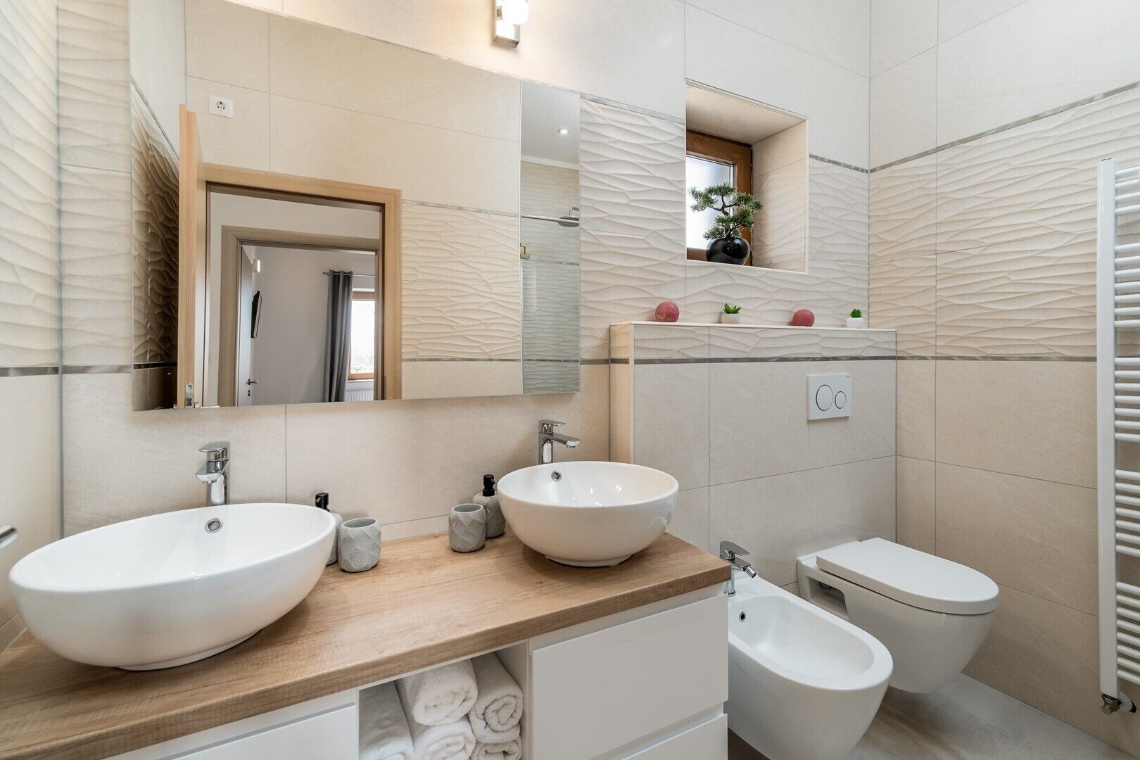 Et moderne badeværelse med to håndvaske, en bidet og et toilet.