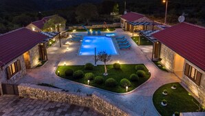 Resort com piscina, espreguiçadeiras e edifícios de pedra com telhados vermelhos.