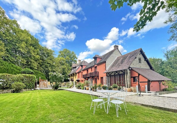 A traditional chalet-style building with a well-maintained lawn and outdoor seating area. - Le Moulin de Fourges (Vexin-sur-Epte)