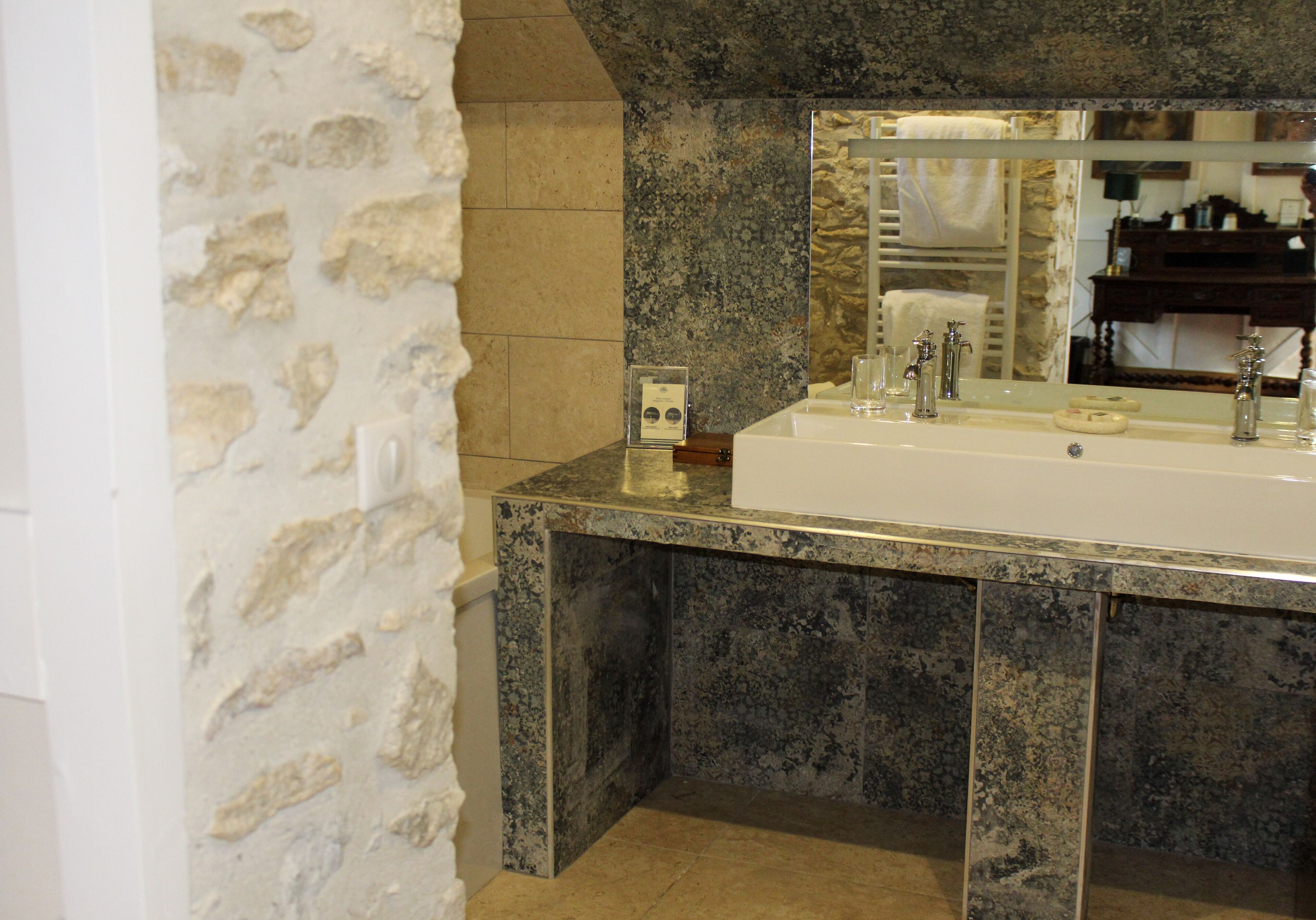Une salle de bain avec un mur en pierre, un lavabo et un miroir.