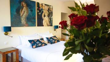 Een slaapkamer met een groot bed, twee wandlampen en een schilderij boven het bed.