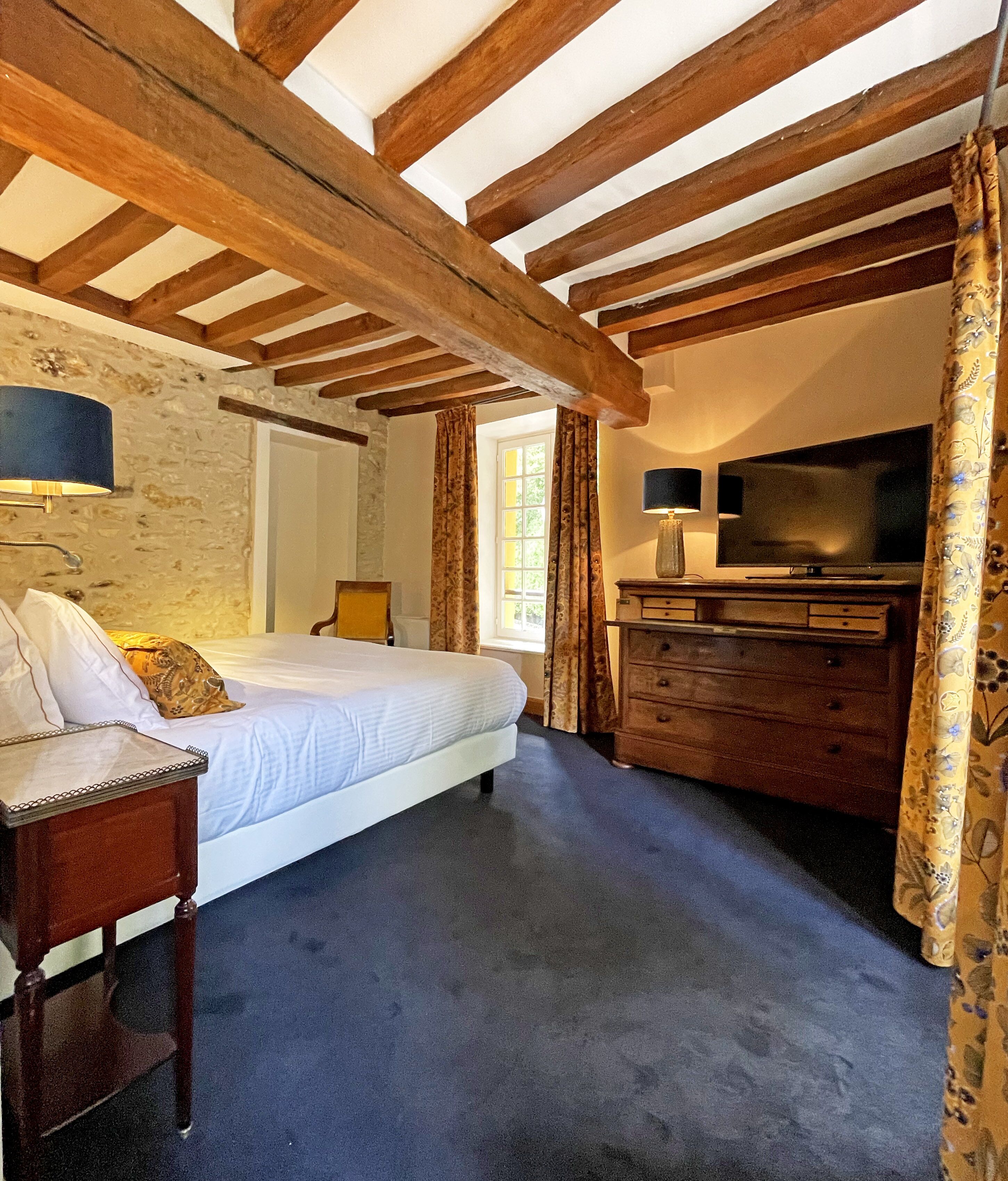 Une chambre à coucher avec un lit, une commode, un téléviseur et une lampe.