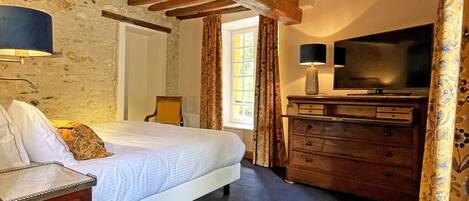Une chambre à coucher avec un lit, une commode, un téléviseur et une lampe.
