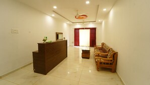 A spacious room with a reception desk, a wooden sofa, and a ceiling fan. - Treebo Infinity View Mahabaleswar (Jaoli)