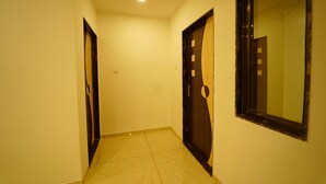 A narrow hallway with two doors, one with a circular window and the other with a rectangular window. - Treebo Infinity View Mahabaleswar (Jaoli)