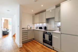 A modern kitchen with a built-in oven, a sink, and a countertop with a kettle and toaster.