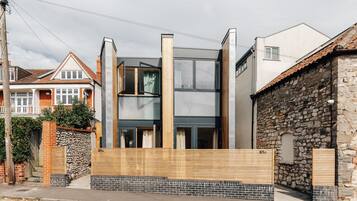 A modern two-story house with a stone facade and a wooden fence.