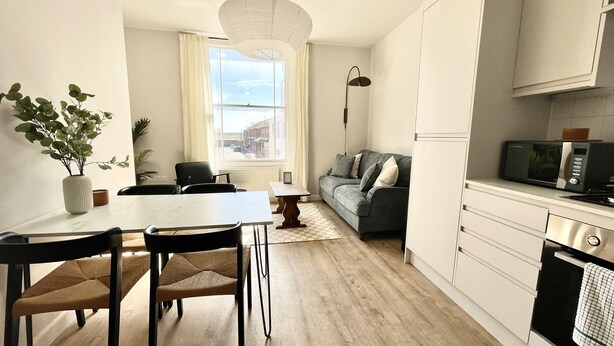 A modern kitchen with a dining area, a sofa, and a view of the street. - Spacious and Stylish Central Bristol Base (Bristol)