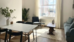 A modern dining area with a white marble table, black chairs, a potted plant, and a view of a street through a large window. - Spacious and Stylish Central Bristol Base (Bristol)