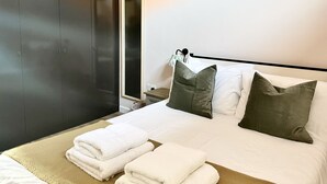 A hotel room with a large wardrobe, a bed with white bedding and green pillows, and a bedside table with a lamp. - Spacious and Stylish Central Bristol Base (Bristol)