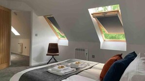 A bedroom with a bed, two skylights, a chair, and a radiator. - Beautiful Cosy Rural Retreat with Parking! (Winford)
