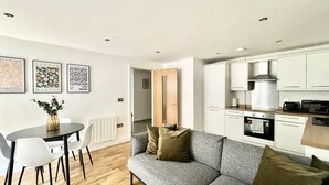 A modern apartment with a dining area, a grey sofa, and a kitchen. - Modern apartment in Bristol City Centre (Bristol)