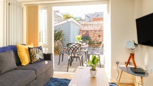 A living room with a sofa, a coffee table, and a TV on a stand. - Park Mews (Weymouth)
