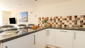 A modern kitchen with white cabinets, a granite countertop, and a tiled backsplash. - Park Mews (Weymouth)