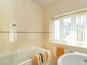 A bathroom with a bathtub, a shower, and a window with blinds.
