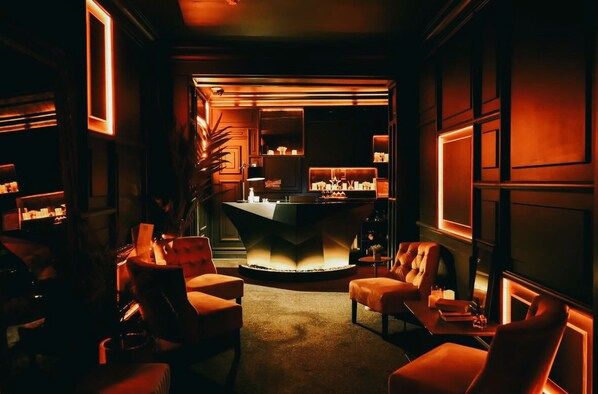 A dimly lit lounge area with a central bar and seating.