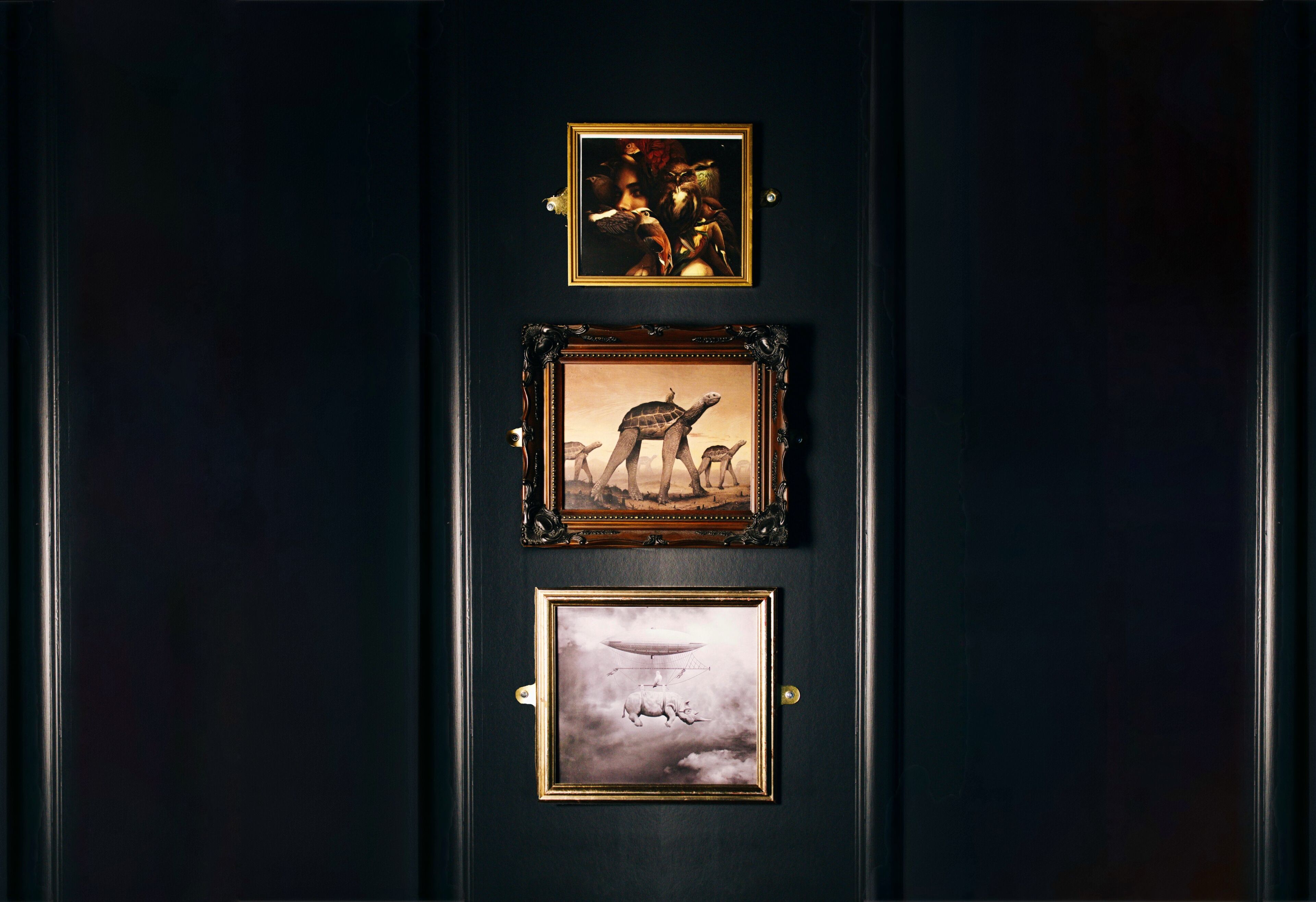 Three framed artworks on a dark wall.