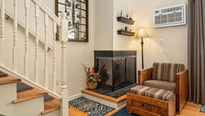Cozy living area with a fireplace, comfortable seating, and a staircase leading to an upper floor.