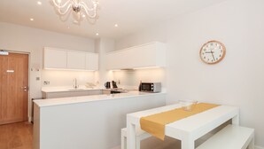 A modern kitchen with white cabinetry, a built-in microwave, and a wooden door.