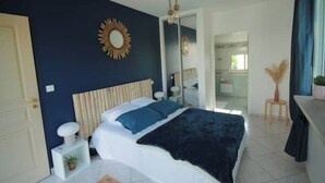 A bedroom with a bed, bedside tables, a mirror, and a view into the bathroom.