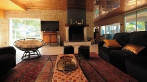 A spacious living room with a fireplace, a large TV, and a comfortable seating area with a sofa and a chair.
