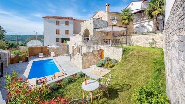 Une villa dotée d’une piscine, d’un espace extérieur aménagé et d’un mur en pierre.