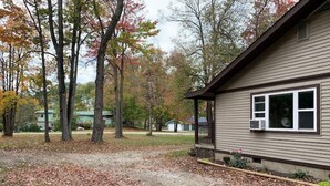 A residential property with a detached house, a covered porch, and a yard with scattered leaves.